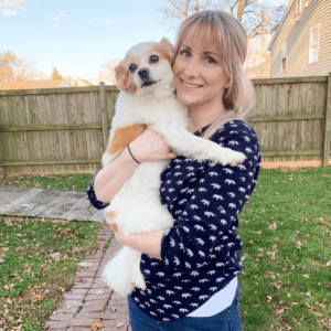 Team member Alaina smiling with brown and white small dog