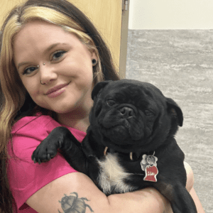 Team member Alina smiling with black pug