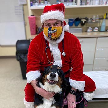 Dr Brenda Moulder wearing a santa suit, posing with a dog