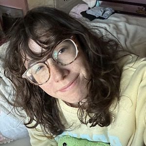 female with should length brown wavy hair and glasses