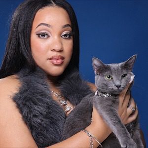 Female with gray furry vest holding a gray cat