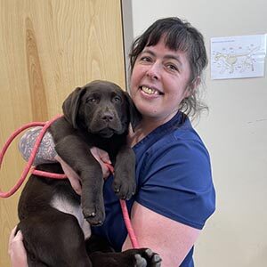 Staff member Ruthie with puppy brown lab